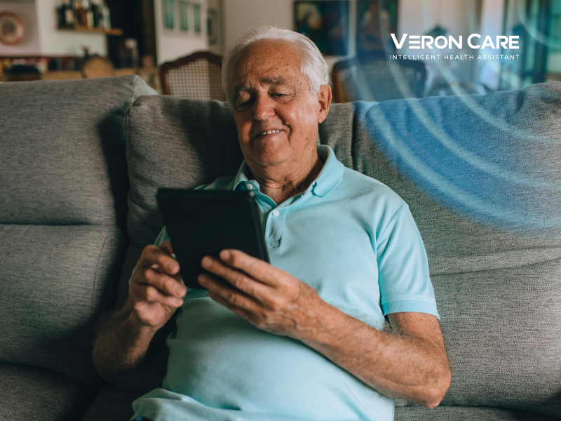 Elderly man using a tablet at home while supported by intelligent health monitoring technology
