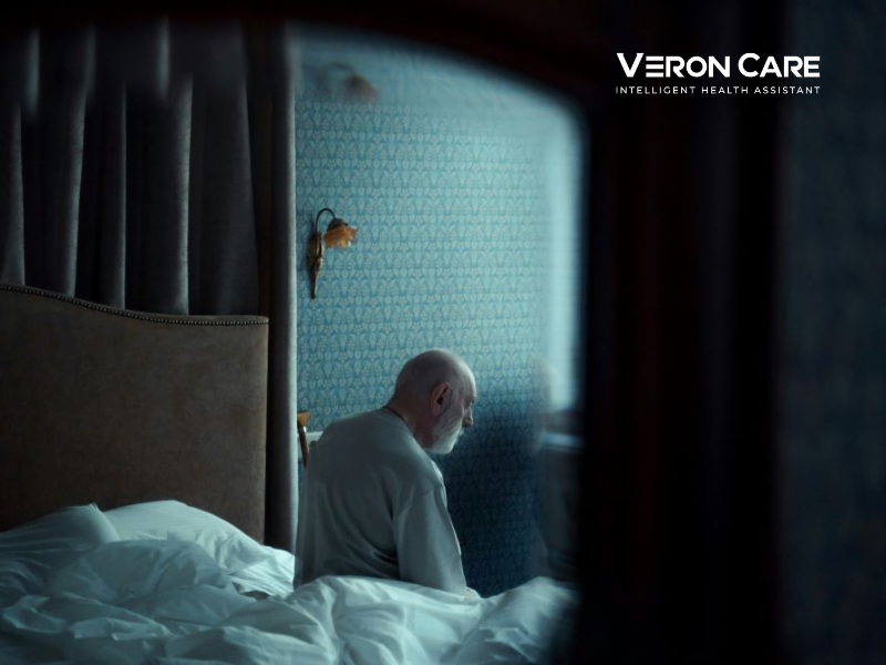 Elderly man sitting on the edge of his bed at night, highlighting nighttime safety risks for seniors at home.
